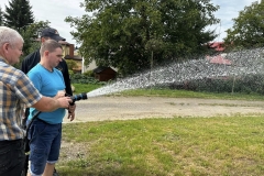 Uczestnik ŚDS leje wodę z węża strażackiego 