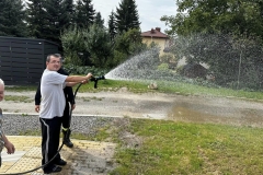 Uczestnik ŚDS leje wodę z węża strażackiego 