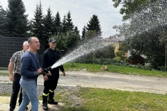 Uczestnik ŚDS leje wodę z węża strażackiego 