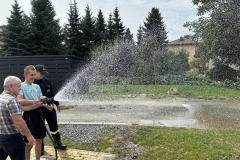 Uczestnik ŚDS leje wodę z węża strażackiego 