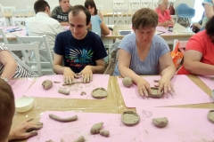 Uczestnicy ŚDS podczas warsztatów ceramicznych i linorytu, praca w glinie