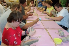 Uczestnicy ŚDS podczas warsztatów ceramicznych i linorytu, praca w glinie