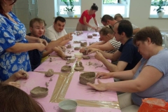 Uczestnicy ŚDS podczas warsztatów ceramicznych i linorytu, praca w glinie