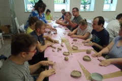 Uczestnicy ŚDS podczas warsztatów ceramicznych i linorytu, praca w glinie